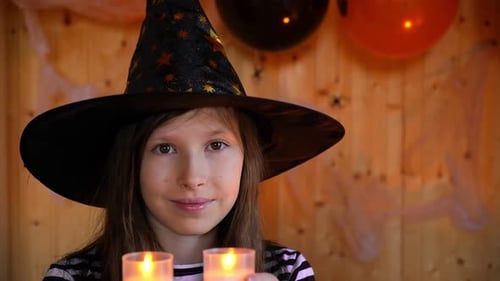 Young Girl Smiling Wearing Witch Hat Holding Candles