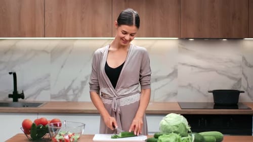 Smiling Woman Cutting Cucumber in Modern Kitchen