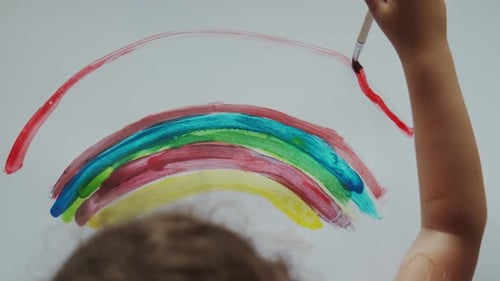 Child Painting a Colorful Rainbow with Paint