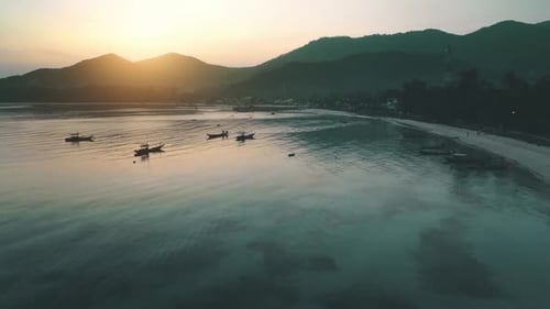 Evening Sun Shines Boats at Sea Behind Mountains Aerial