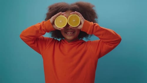 Smiling Girl Playing with Orange Halves