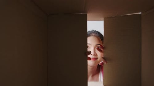 Woman Unboxing Plant in Cardboard Box Indoors