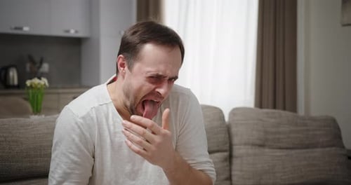 Erwachsener Mann drückt Ekel auf dem Sofa aus