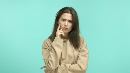 Nachdenkliche junge Frau mit Kapuze, die den Kopf berührt und beim Nachdenken intensiv aussieht, dann eine Idee einbringen