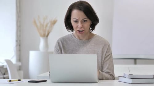 Angry Woman Working on a Laptop at Desk