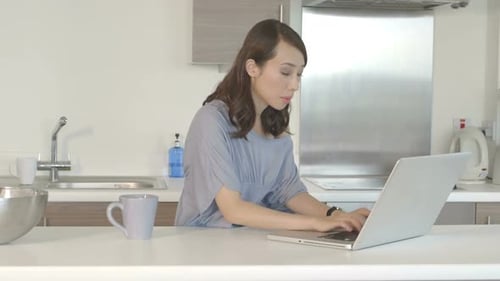 Woman Typing on Laptop and Drinking Coffee at Home