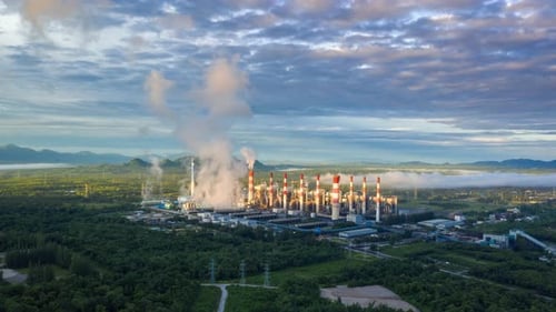 Aerial view over coal-fired power plant at sun dawn with smoke from cooling,