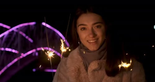 Woman Smiling with Sparklers at Night Celebration