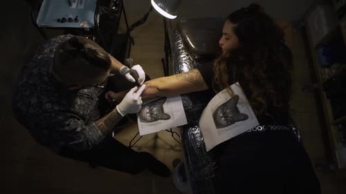 Tattoo Artist Inking Woman's Arm with Cat Portrait