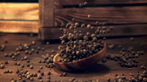 Super Slow Motion Plate with Peas of Black Pepper Falls on the Table