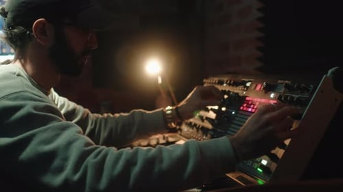 Man Creating Music on Keyboard Synthesizer in Studio