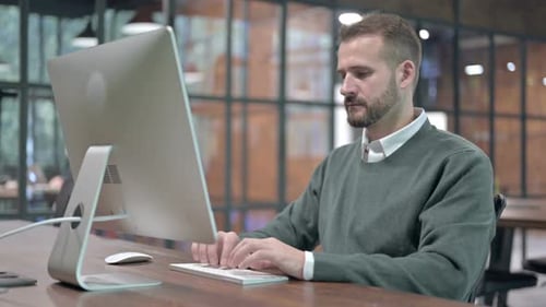 Man Typing at Computer in a Modern Office