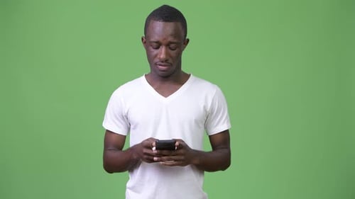 Young African Man Using Phone Against Green Background