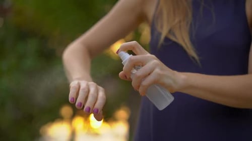 Woman Sprays Insect Repellent on Arm Outdoors