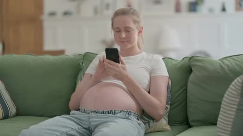 Pregnant Woman Uses Cell Phone on Green Couch