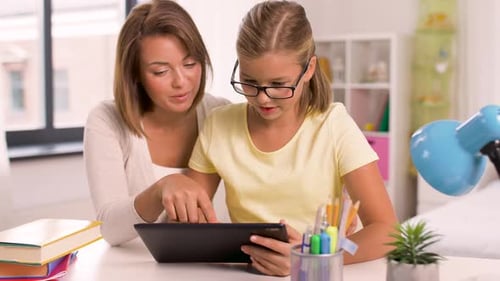 Woman and Girl Using Tablet at Table Indoors