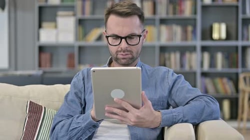 Man Using Tablet While Relaxing on Couch