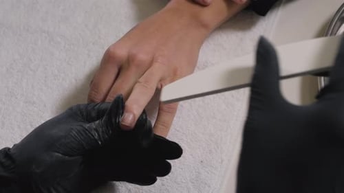 Manicurist Filing Nails in a Nail Salon