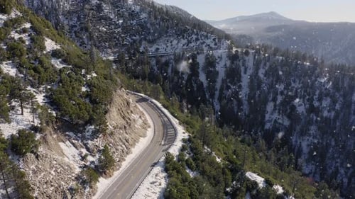 Aerial Shot of Winding Mountain Road in Snowing Winter Landscape