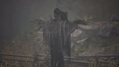 Terrible Scarecrow in Dark Cloak and Dirty Hat Stands Alone in Autumn Field