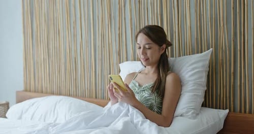 Woman Using Smartphone in Bed in the Morning