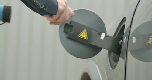 Man Plugs Electric Charger Into Car Port