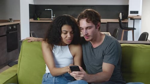 Couple Relaxing on Couch with Smartphone at Home