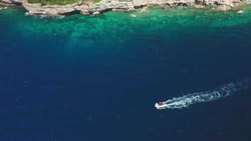 Motorboat Sails Along Sea Past Steep Cliffs at Resort