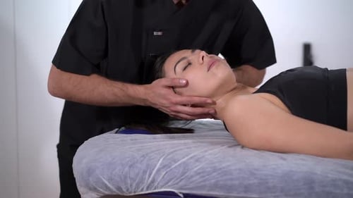 Physiotherapist examining neck of female athlete in clinic