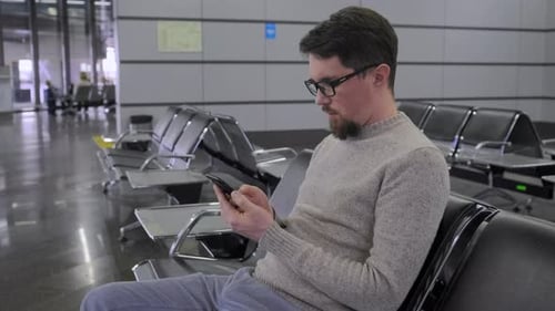 Man Is Scrolling Screen of Smartphone in Departure Lounge