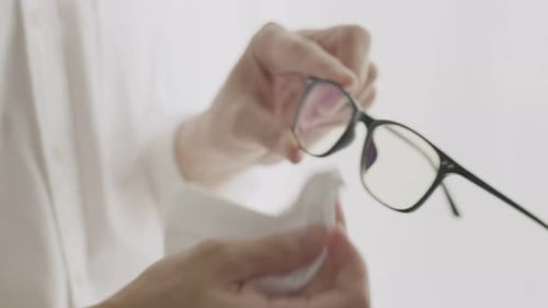 Close Up of Hands Cleaning Black Framed Glasses