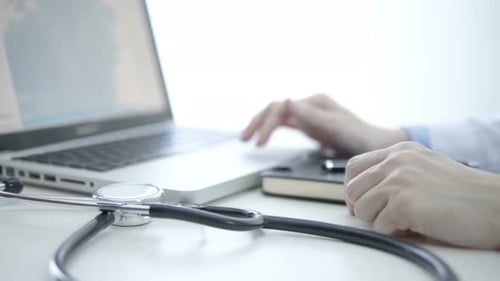 Doctor Typing on Laptop in Bright Office