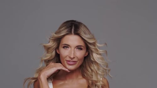 Studio portrait of young and beautiful blond woman over grey background.