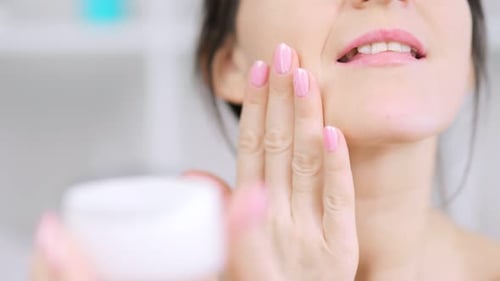 Woman Applies Moisturizing Cream to Her Face