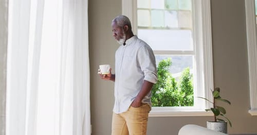 Senior Adult Drinking Coffee by Bright Home Window
