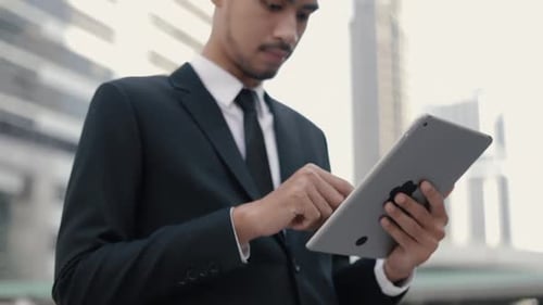Close-up portrait businessman manager in a black suit using his tablet typing message.