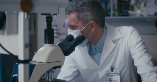 Scientist Studying Sample in Microscope