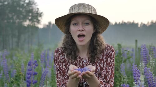 Woman Blowing Flower Petals in Lupine Field