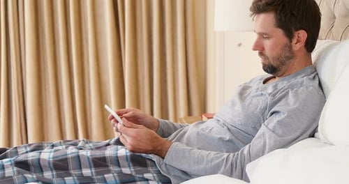 Man Relaxing in Bed Using Digital Tablet