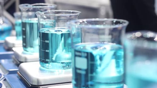 Beakers of Swirling Blue Liquid in Laboratory Setting