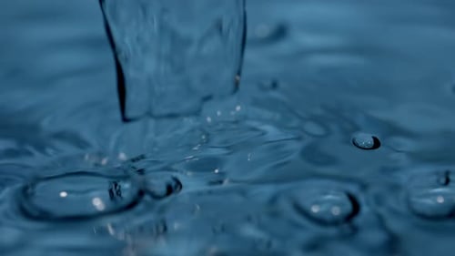 Pouring Water Creates Ripples and Bubbles in Liquid