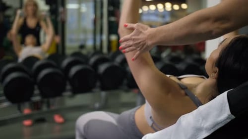 Woman Lifts Dumbbell with Personal Trainer