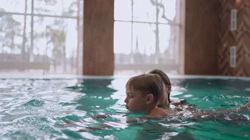 Mutter bringt seinem kleinen Sohn bei, im Pool zu schwimmen Hallenbad im Wellnesscenter