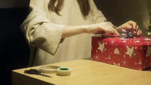 Woman Wrapping Christmas Gift with Bow