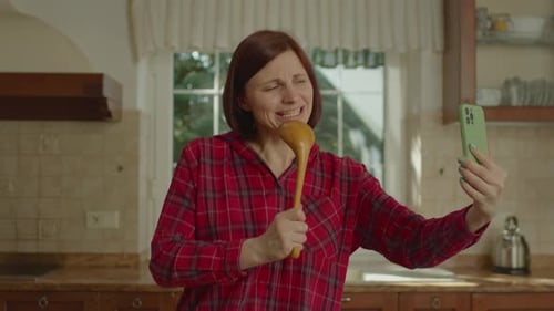 Woman Sings into Spoon, Performs in Kitchen