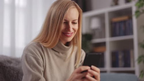 Smiling Woman Using Mobile Phone in Living Room