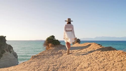 Stylish Boho Woman Walking on Cliff Over Mediterranean Sea