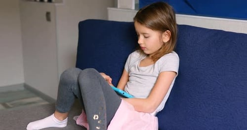 Young Girl Using Tablet at Home on Couch