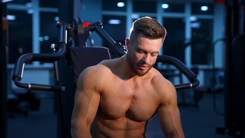 Handsome man with muscles posing at the camera in the gym