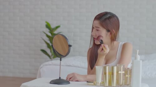 Woman Applies Makeup with Brush at Vanity